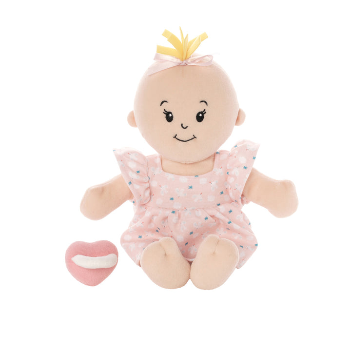 soft baby doll with peach skin and blonde hair tuft in a pink dress seated with a pink magnetic pacifier off to the side